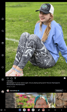 a girl wearing a hat and leggings sits on a grassy field