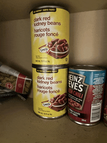 a can of dark red kidney beans sits next to a can of heinz eve 's hot chili