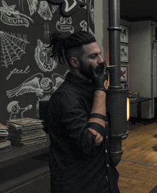 a man in a black shirt smoking a cigarette in front of a chalkboard that says seun