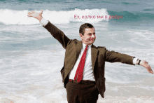 a man in a suit and tie with his arms outstretched on the beach