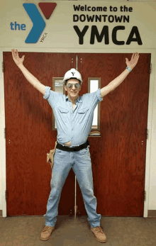 a man wearing a hard hat and sunglasses stands in front of a door that says welcome to the downtown ymca