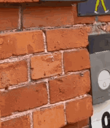 a person is holding a piece of paper in front of a brick wall with a sign on it .