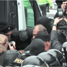 a group of people are gathered in front of a vehicle and one of them is wearing a helmet that says po