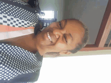 a woman wearing a black and white polka dot shirt smiles