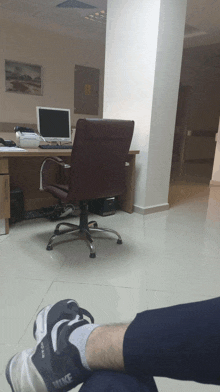 a person wearing nike shoes sits in front of a desk with a computer