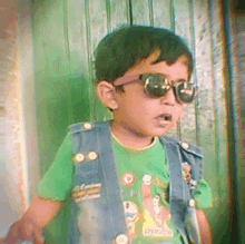 a young boy wearing sunglasses and a green shirt that says spongebob on it