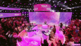a group of people are sitting in front of a stage with a sign that says tout beau