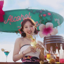 a woman holds a glass of wine in front of a sign that says alcohol