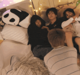 a group of people laying on a bed with a stuffed panda bear