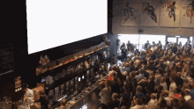 a crowd of people are gathered in front of a large screen