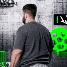 a man with a tattoo on his arm stands in front of a wall with graffiti on it
