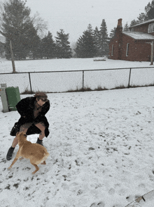 a woman playing with a dog in the snow