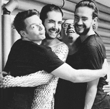 a black and white photo of four men hugging