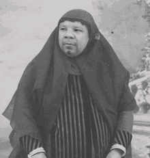 a black and white photo of a woman wearing a striped dress and a veil