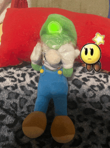 a stuffed mario with a green hat and blue overalls is sitting on a leopard print blanket