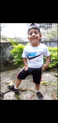 a little boy wearing a white nike shirt and black shorts