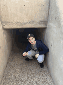 a young man wearing a hat with the letter t on it is kneeling in a tunnel