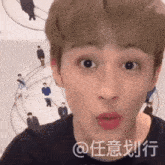 a young man is making a funny face in front of a wall with people on it .