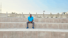 a man in a blue shirt is sitting on a set of steps with kamar written on the bottom