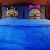 two cartoon characters are laying on a bed with a blue comforter