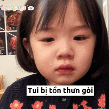 a little girl with a tear coming out of her eye and a sticker that says tui bi ton thun goi