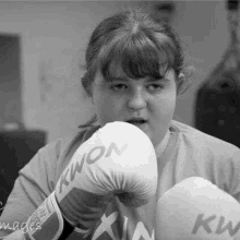 a young girl is wearing boxing gloves and a t-shirt .