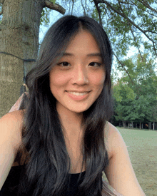 a woman with long black hair is smiling for the camera