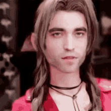 a man with long hair and a choker is wearing a red jacket and a red shirt .