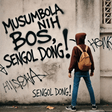 a person standing in front of a wall that has graffiti on it that says musumbola bos nih sengol dong