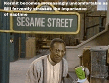 kermit is standing in front of sesame street sign