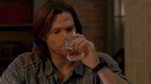 a man is drinking a glass of whiskey