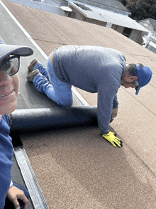 a man is kneeling on a roof with a roll of rubber on it