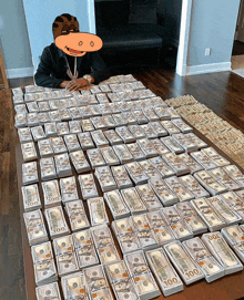 a man is sitting on a table covered in stacks of 100 dollar bills