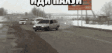 a car is driving down a road with a billboard in the background that says ' i am a man '