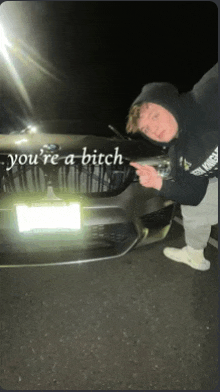 a man is standing in front of a car that says you 're a bitch on it