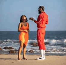 a man and a woman are standing on a beach talking