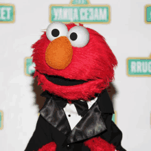 elmo is wearing a tuxedo and bow tie in front of a sesame street sign