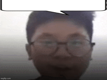 a blurry picture of a man wearing glasses and a speech bubble above his head .