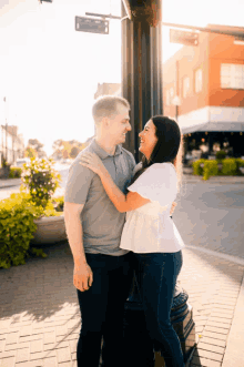 a man and a woman are standing next to each other on a street