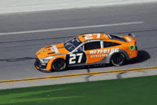 a race car with the number 27 on the side is driving down a race track .