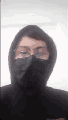 a person wearing glasses and a black mask with a hood