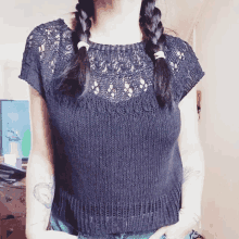 a woman with braids is wearing a knitted top