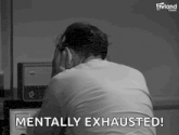 a man is sitting in front of a radio with his head in his hands and says mentally exhausted !