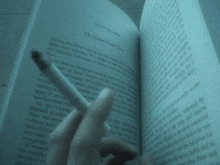 a person is holding a cigarette in front of a book that is opened to chapter five