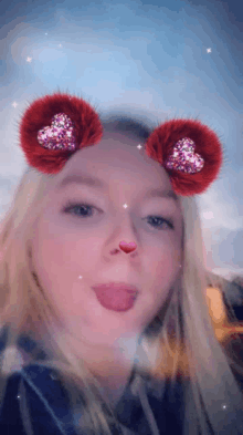 a girl wearing a valentine 's day filter with hearts on her ears sticks out her tongue