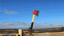 a large red and yellow axe is being thrown in the air by a crane with the words not a building visible in the background