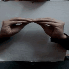 a person is holding a piece of paper in their hands and making a heart shape .