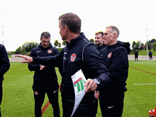 a group of men are standing on a field and one of them is holding a piece of paper with the number 11 on it