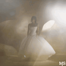 a woman in a white dress is standing in a foggy room with the letters ms below her