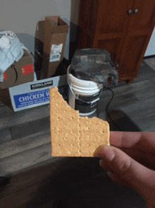 a person holding a cracker in front of a box of kirkland chicken